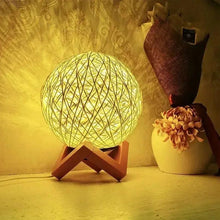 Decorative LED bedside lamp with glowing yellow rattan globe shade and wooden tripod stand