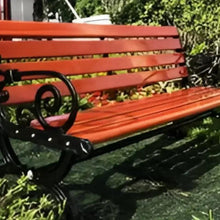 Orange slat bench with black scroll armrest and ornate metal leg