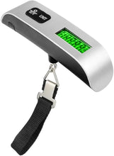 Silver luggage scale with green backlit LCD and black wrist strap, metal hanging hook