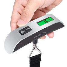 Digital luggage scale in hand with green LCD reading, black grip handle, metal hook