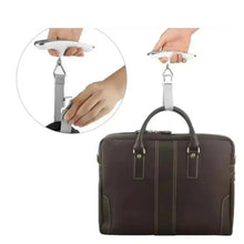 Portable digital luggage scale clipping onto a brown bag handle