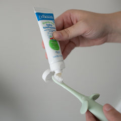 Dr Browns baby toothpaste on green infant toothbrush 0-3 years with soft silicone whale handle