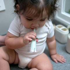 Dr Browns mint silicone infant toothbrush 0-3 years used by a baby sitting on bathroom counter