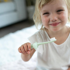 Dr Browns infant toothbrush 0-3 years mint green ergonomic handle safety stopper held by smiling toddler
