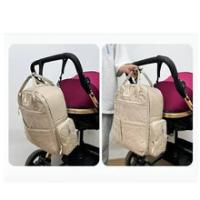 Light pink baby travel backpack attached to a stroller with quilted front and zip closure.