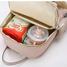 Open light pink baby travel bag with baby bottle container and wipes inside compartment.