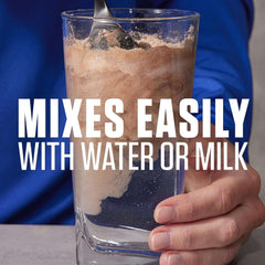 Dymatize Elite Whey Protein Rich Chocolate powder mixing in glass with spoon and hand showing it mixes easily with water or milk
