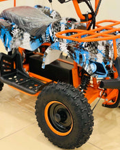 Orange electric quad bike with blue camo wrap, black rear suspension, and thick tires