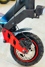 Electric scooter rear wheel with disc brake and red swingarm on black frame.