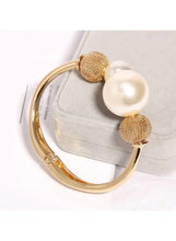 Gold-tone open cuff bracelet with textured mesh ball and large white pearl accent