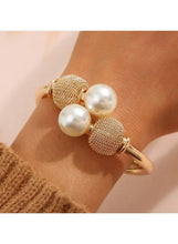 Gold-tone pearl bracelet on wrist with textured mesh beads and three white pearls