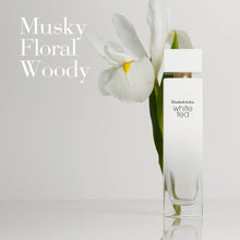 White perfume spray bottle with gold cap beside a white flower