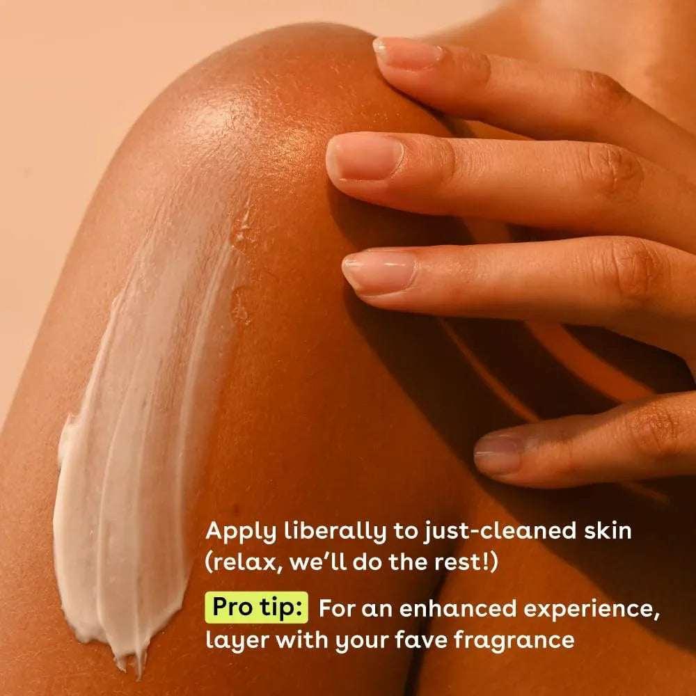 Person applying white body moisturizer cream to an arm with fingertips