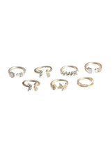 Gold-tone 7-piece fashion ring set with sparkling stones, laid out for viewing.