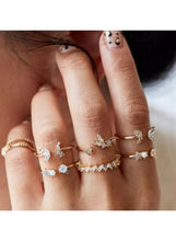 Gold-tone fashion ring set on hand with clear and light-blue stones, stacked styles.