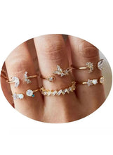 Gold-tone fashion rings with clear stones on hand, including cluster and band styles.