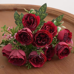 Huitich artificial mini peony bouquet with deep red flowers and green leaves on wooden surface