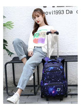 Purple galaxy-pattern wheeled backpack standing upright with top handle and front pocket