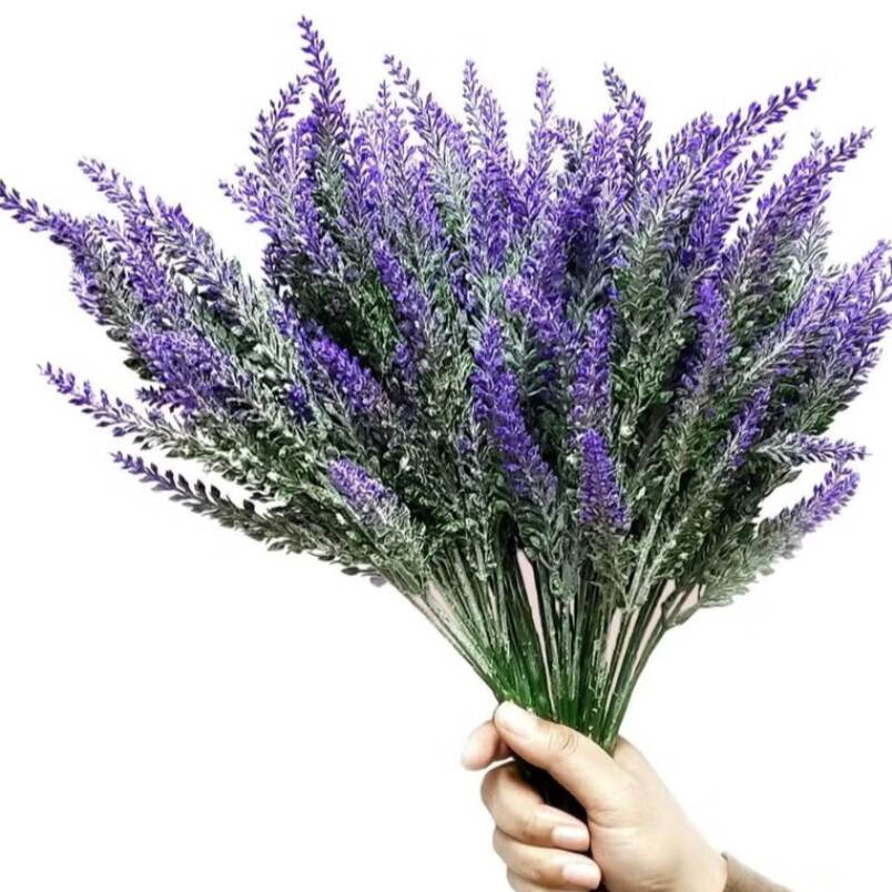 Hand holding a bouquet of artificial lavender flowers decor with green stems and purple blossoms