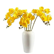 Artificial yellow orchid flowers in white ceramic vase