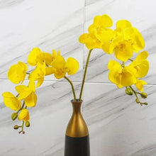 Artificial yellow orchid flowers in gold metallic vase