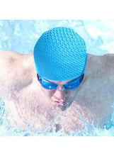 Blue silicone swim cap with textured dots, worn under goggles