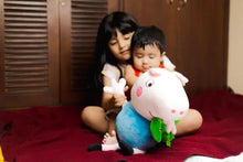 Pink and blue plush pig doll with green dinosaur companion, seated pose.
