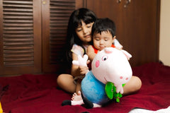 George Buddy soft toy 19x10cm held by a toddler with an older sibling in the background on a red blanket