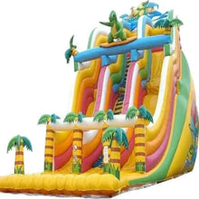 Inflatable dinosaur water slide with rainbow lanes, green palm accents, blue top