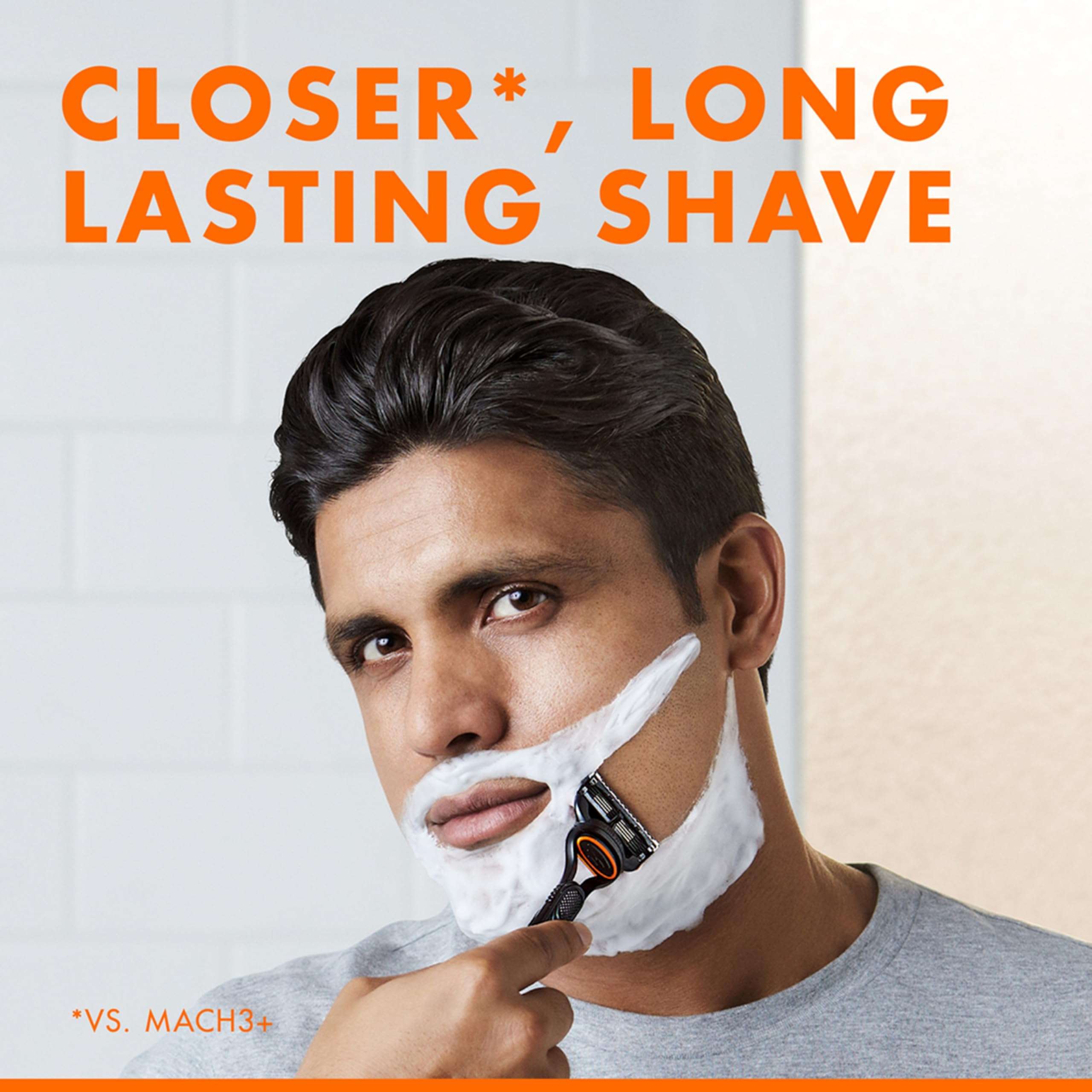 Man shaving with Gillette Fusion 5 men's razor using white shaving cream in a bathroom mirror for a close long lasting shave