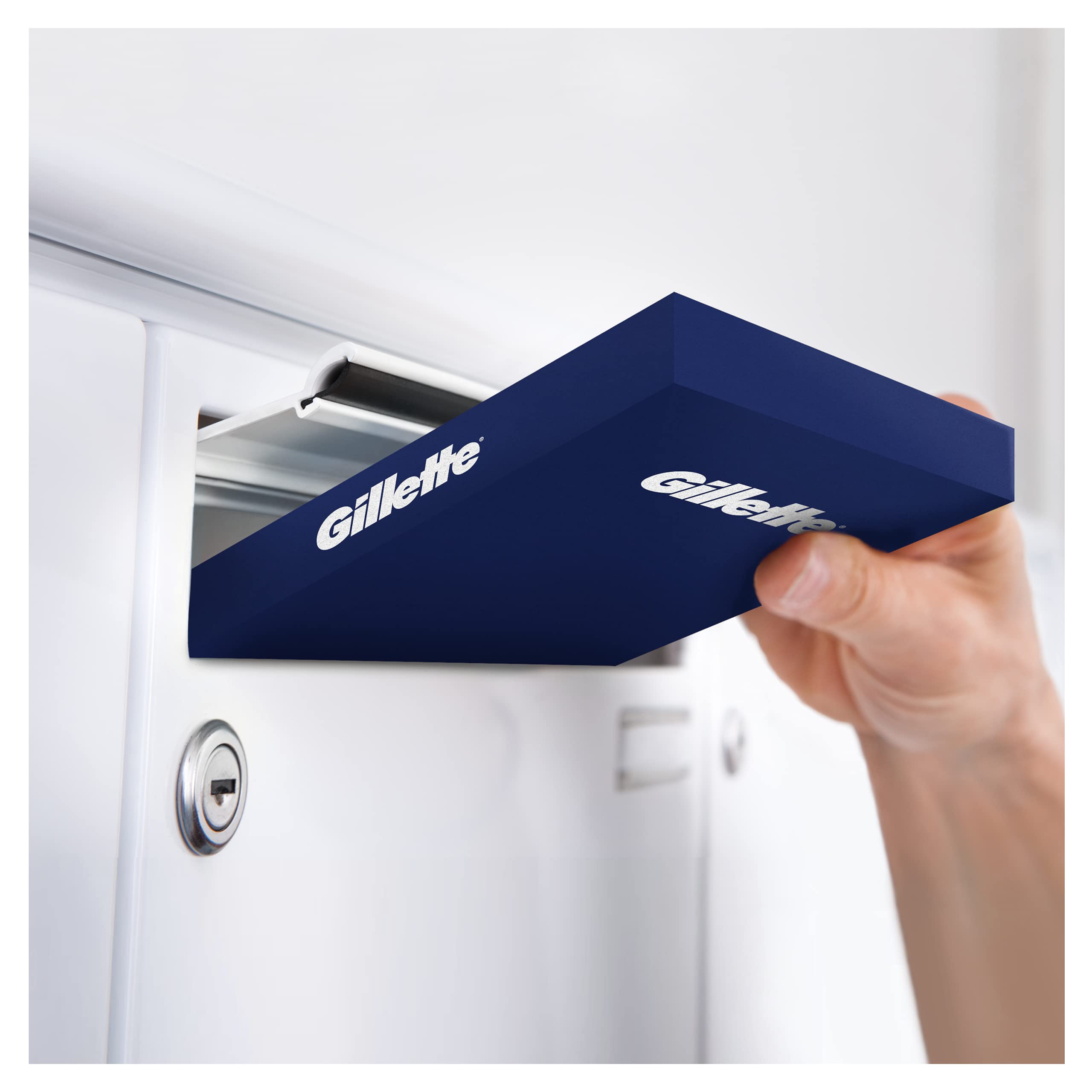Hand placing navy Gillette box into mailbox slot showing Gillette Fusion razor blades 8 pack