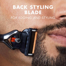 Back styling razor blade on black handle trimming beard hair at cheek.