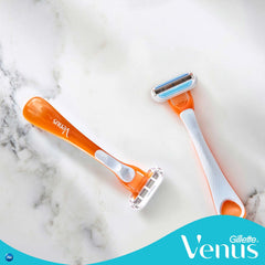 Two orange Gillette Venus disposable razor for women on marble surface showing double blade heads