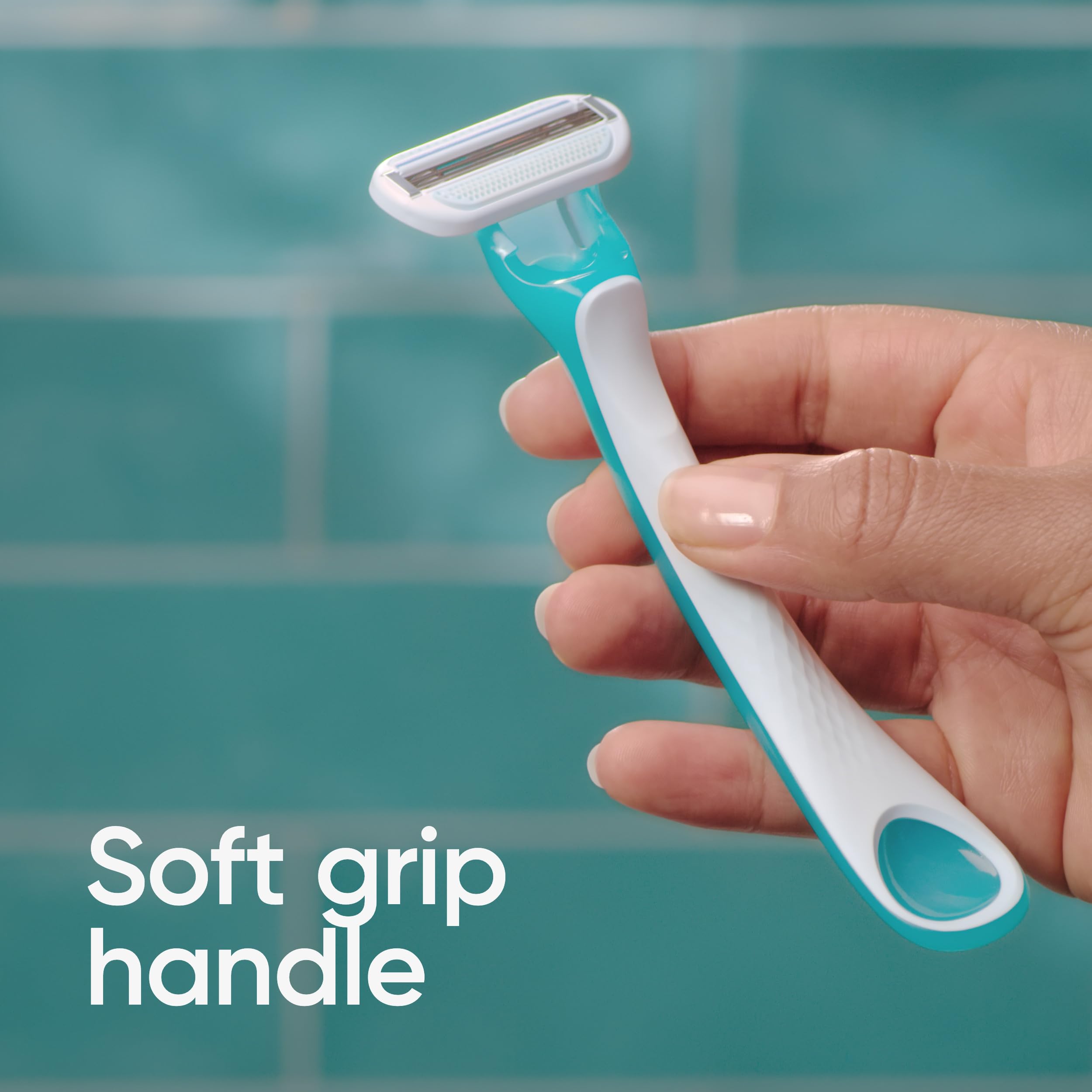 Hand holding Gillette Venus Tropical women's razors with turquoise white soft grip handle against teal tile background