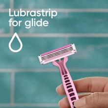 Pink women's disposable razor with three blades, held in hand