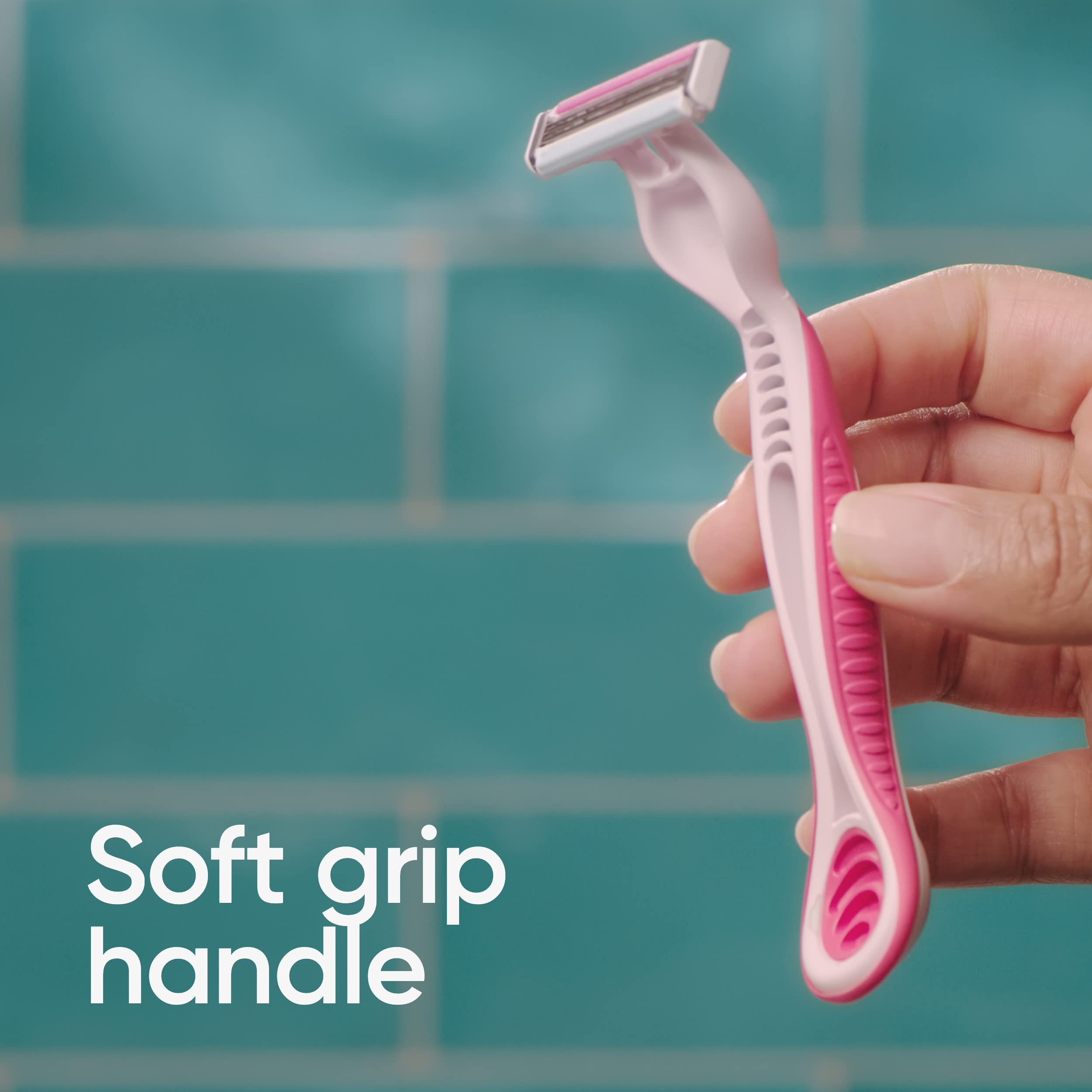 Hand holding pink Venus Simply 3 women's disposable razor with soft grip handle against teal tile background
