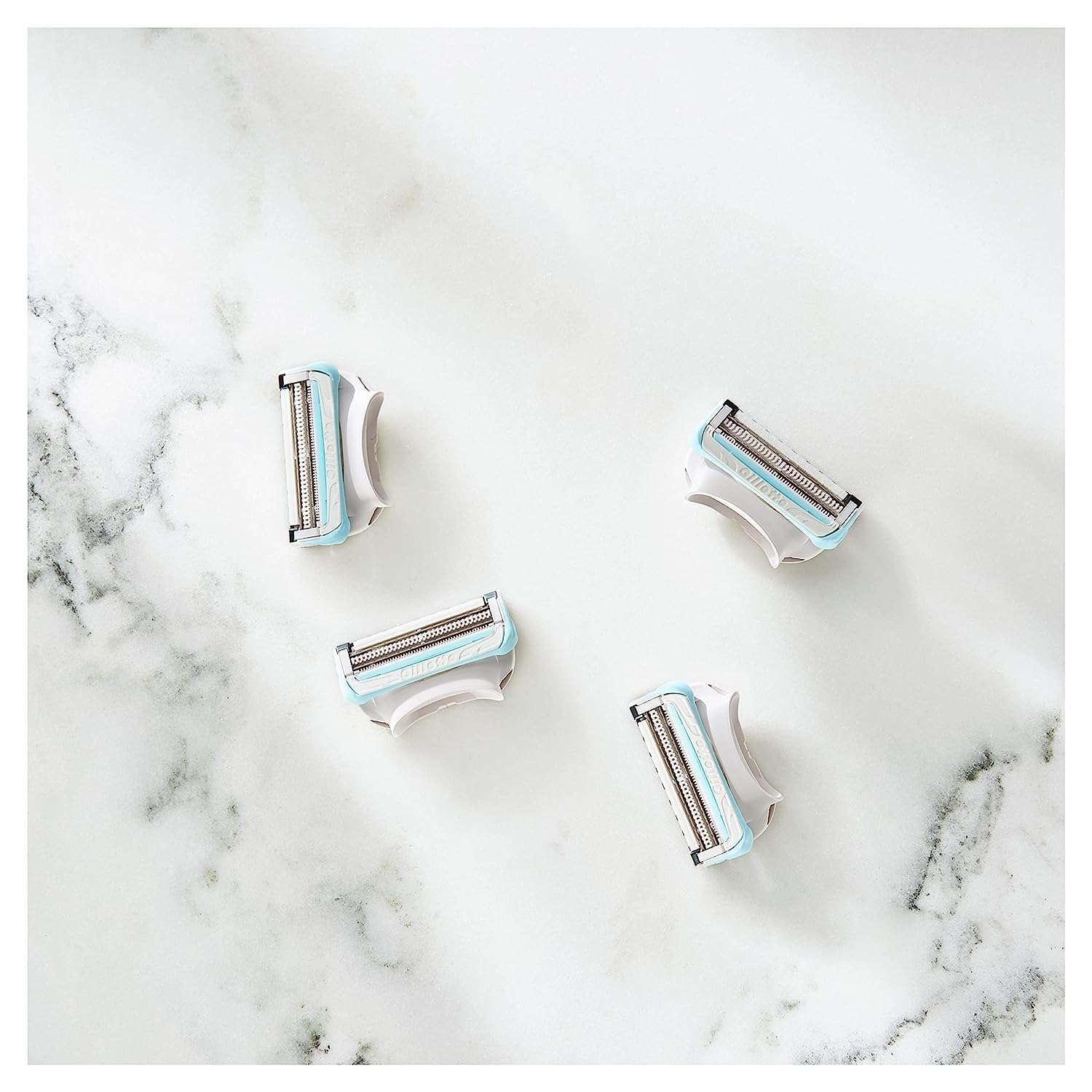 Four Gillette Venus women's bikini razor blades replacement cartridges on white marble surface
