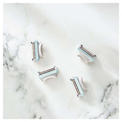 Four Gillette Venus women's bikini razor blades replacement cartridges on white marble surface