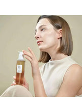 Ginseng Cleansing Oil 210ml bottle in hand with face profile beside the product