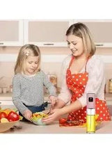 Olive oil spray bottle with stainless cap and clear glass body on a kitchen counter