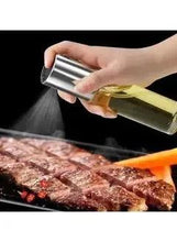 Glass olive oil sprayer bottle with stainless cap releasing a fine mist
