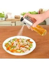 Olive oil spray bottle with stainless cap and clear glass body, dispensing oil