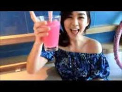 Smiling woman in off shoulder blue top holding a pink glass in cafe showcasing Gluta Berry whitening drink