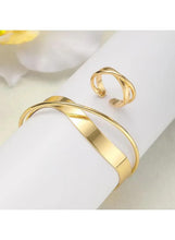 Gold tone alloy cuff bracelet with wide band and matching ring, polished.