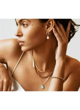 Gold-tone and pearl drop earrings with long hook dangles, worn by model