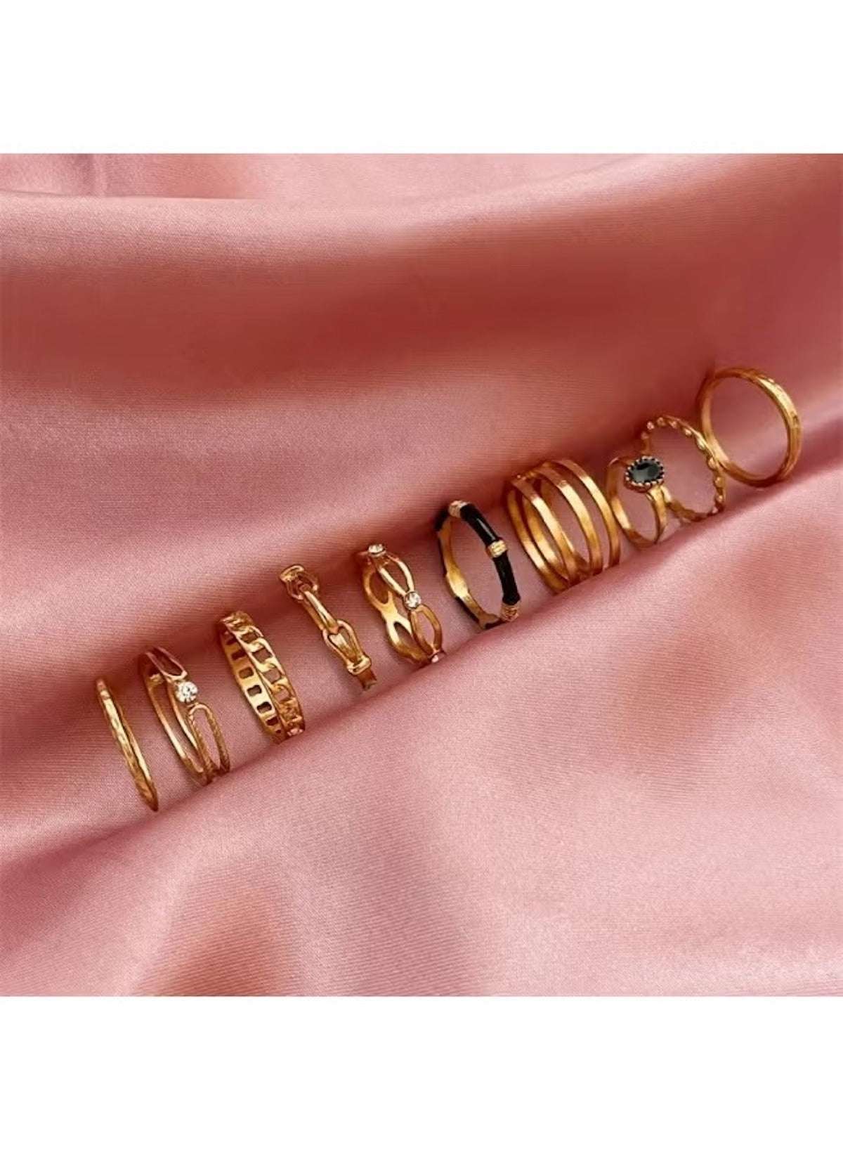 Gold fashion ring set for women featuring various elegant designs arranged on a soft pink satin background