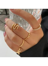 Gold-tone fashion ring set with letter-style ring and bow charm, shown on hand