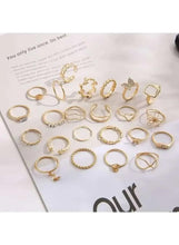 Gold-tone ring set laid out on paper, assorted circular and bow designs