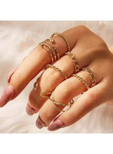 Gold-tone fashion rings on hand with braided bands, hoop ring, and stacked row design