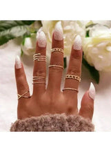 Gold-tone stacking ring set on hand with slim bands and wrapped chain accents